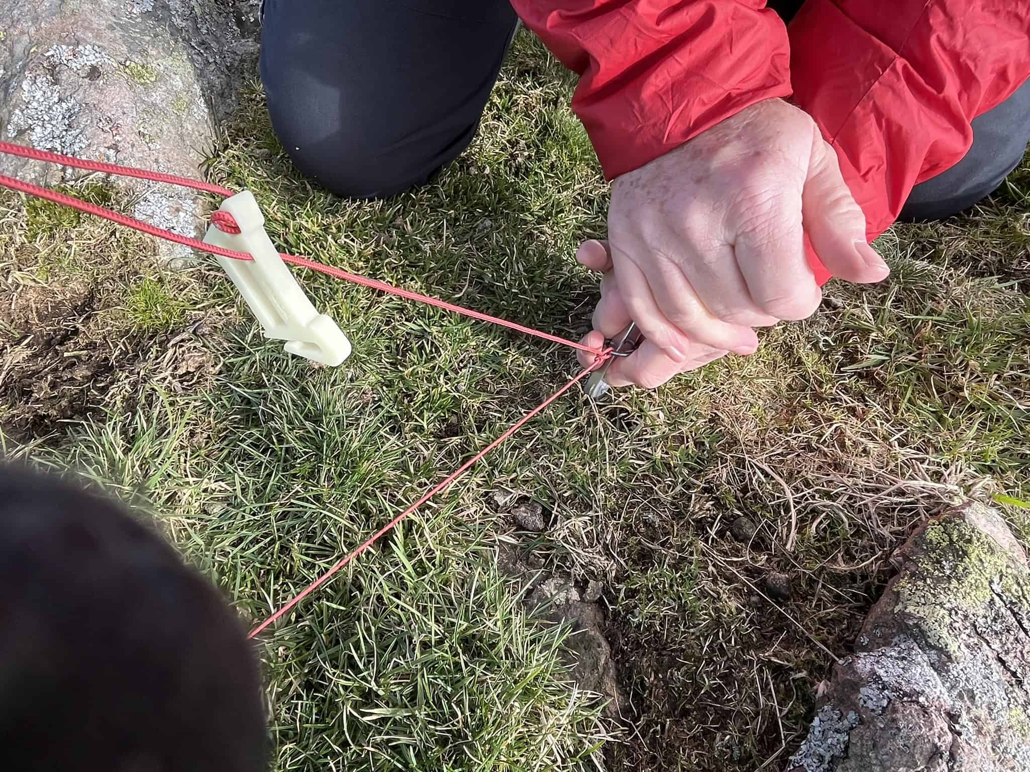 Securing a tent peg and guyline on short mountain grass for a wild camping pitch