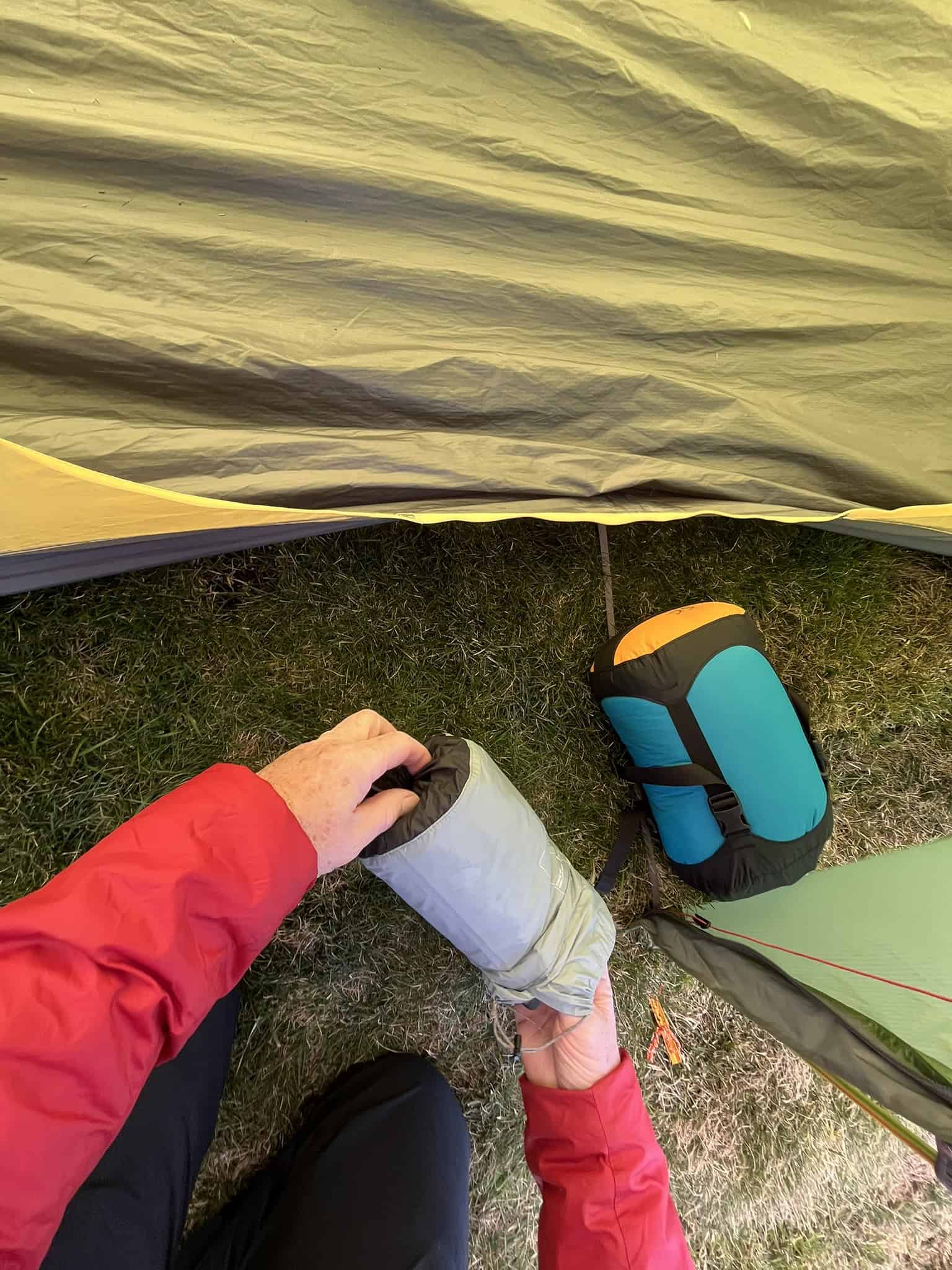 Organising essential wild camping equipment beside a mountain tent