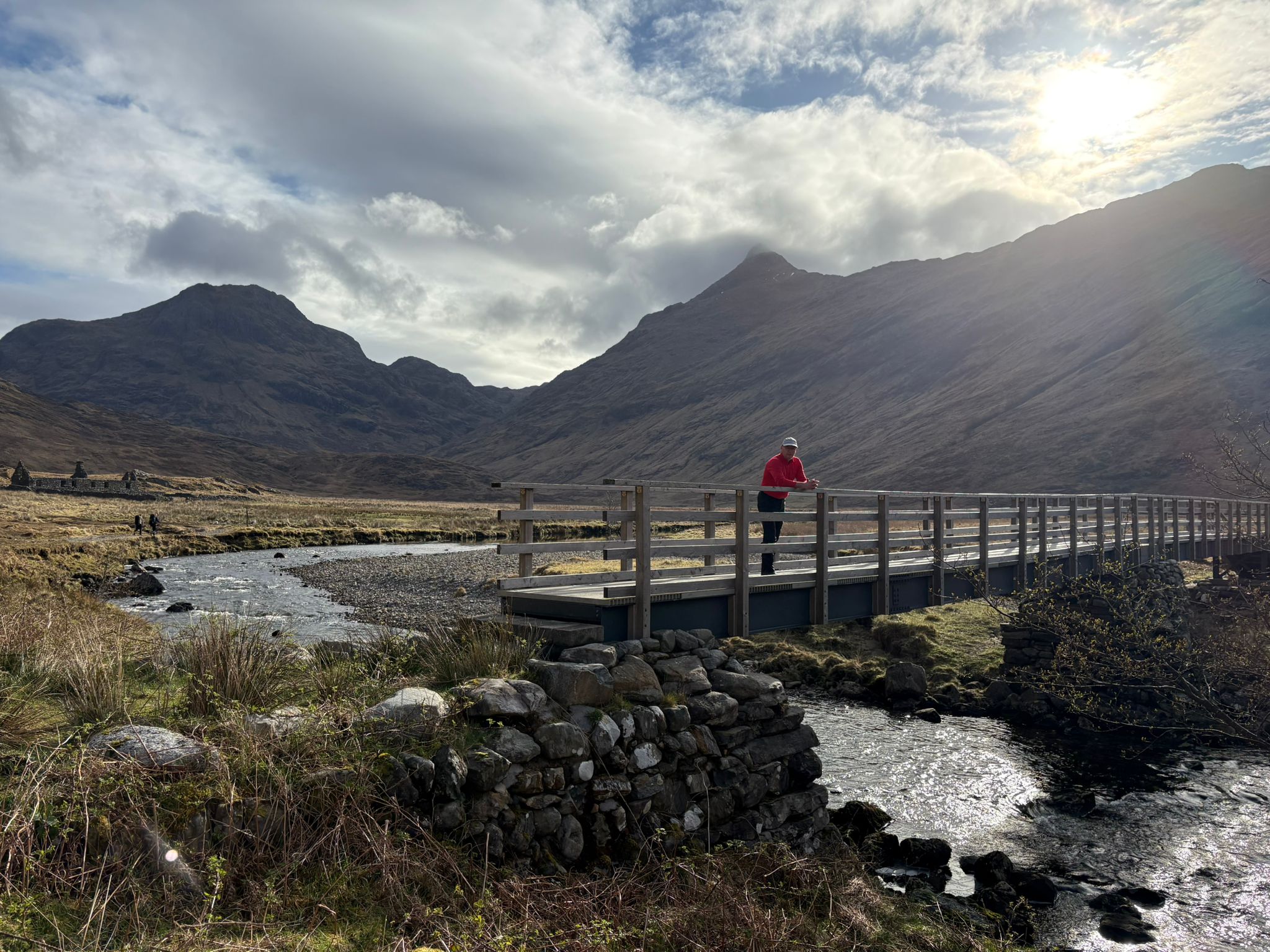 A wooden bridge crossing at the start of a Knoydart walking route with mountains rising ahead