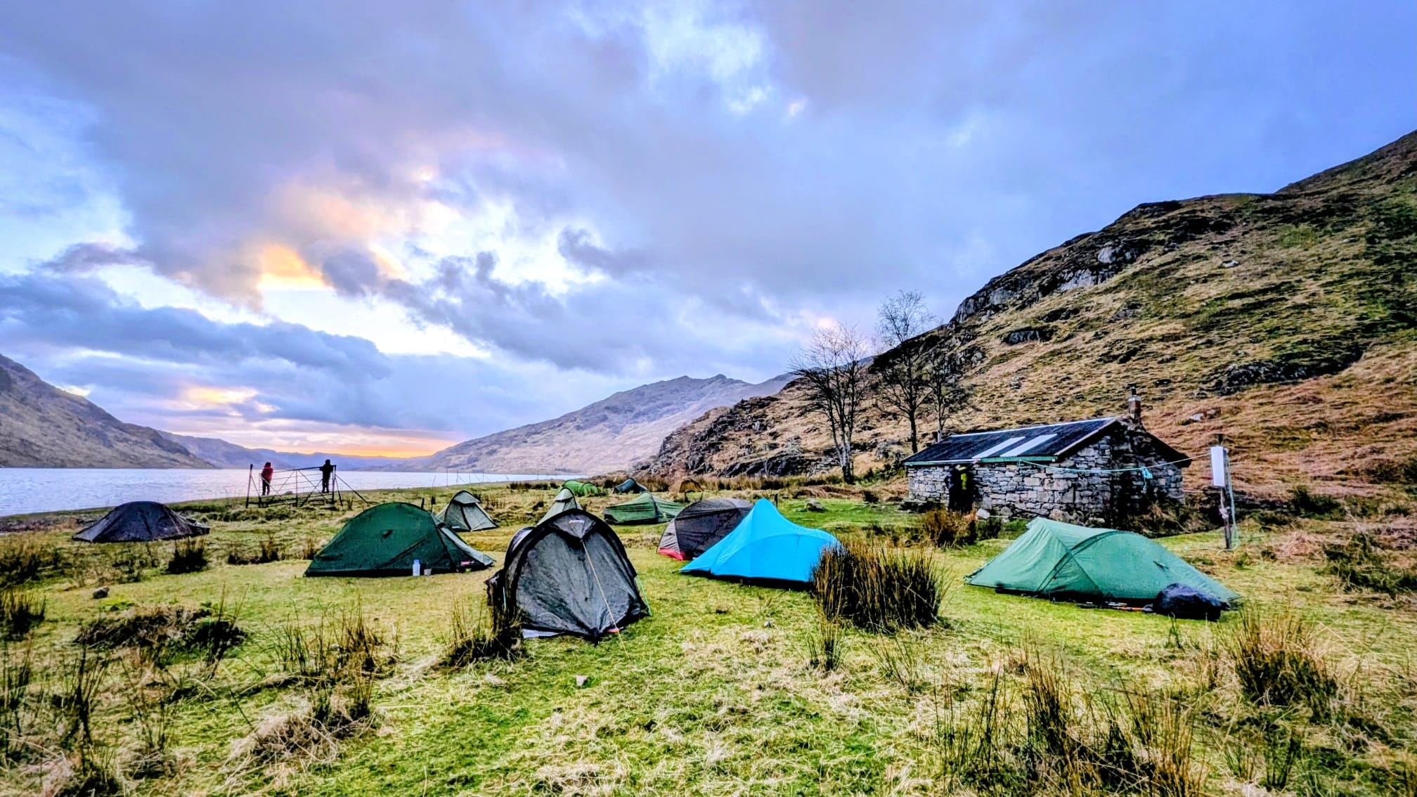 Group wild camping in Knoydart with multiple tents set beside a remote loch